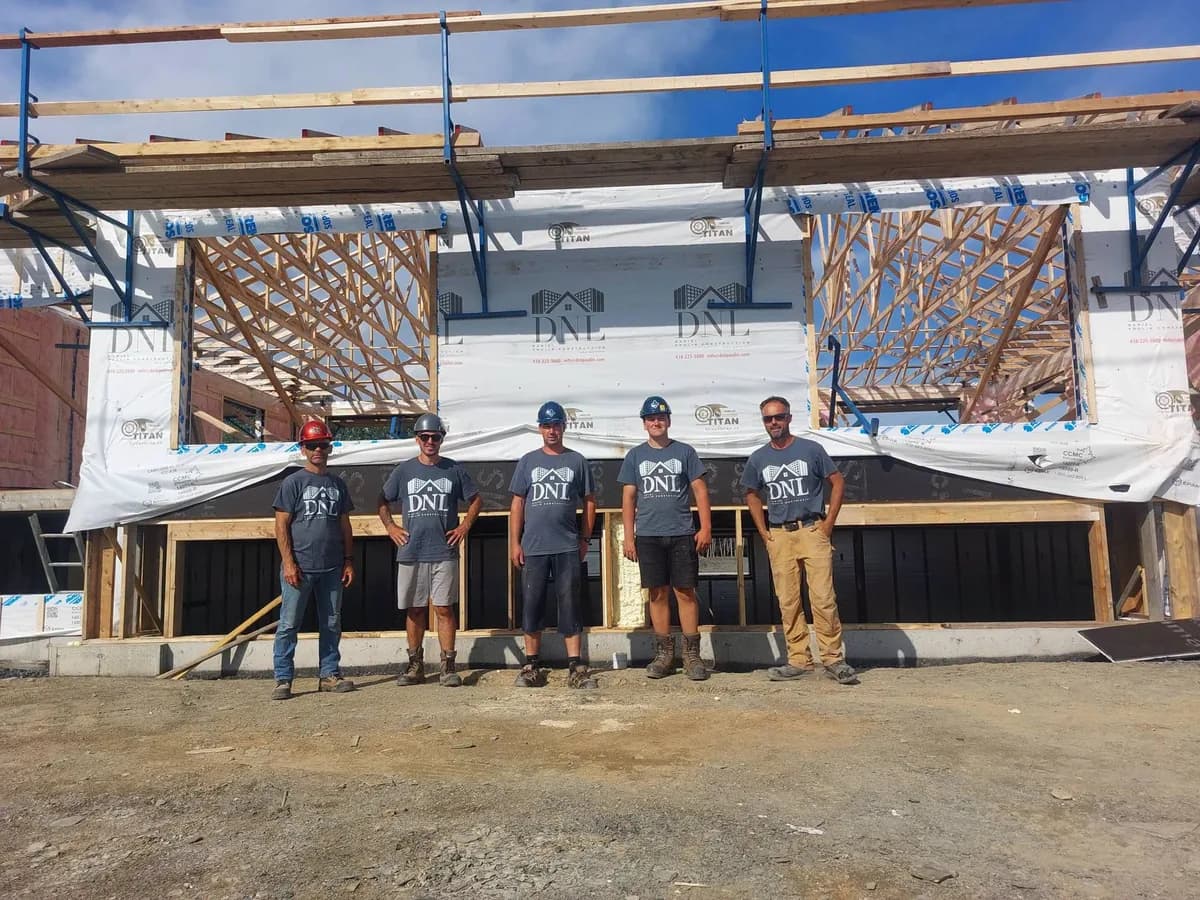 Les cinq membres de l’équipe DNL réunis devant une maison en construction.